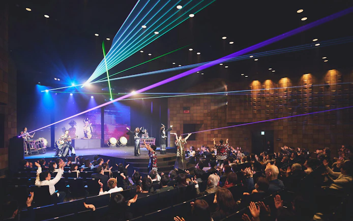 DRUM TAO performance with laser lights at Kyoto theater, audience clapping.