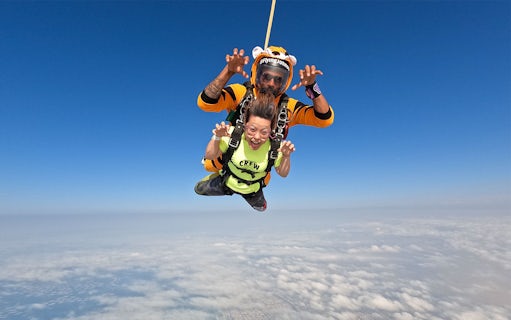 Tandem skydivers over Dubai's Palm Drop Zone with clear blue sky.