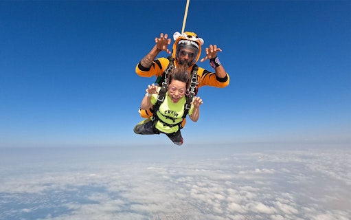 Tandem skydivers over Dubai's Palm Drop Zone with clear blue sky.