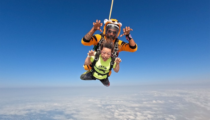 Tandem skydivers over Dubai's Palm Drop Zone with clear blue sky.