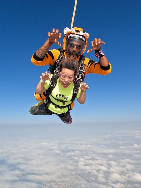 Tandem skydivers over Dubai's Palm Drop Zone with clear blue sky.