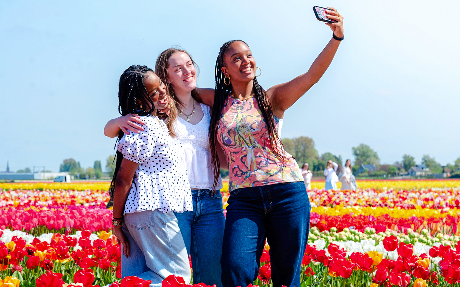 Visitors taking a selfie in a colorful tulip field at Tulip Experience Amsterdam.