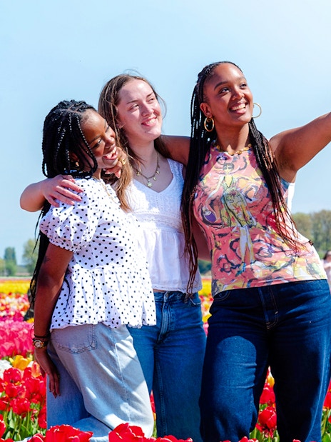 Visitors taking a selfie in a colorful tulip field at Tulip Experience Amsterdam.