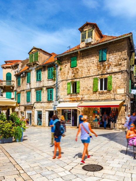 Old town square in Split, Croatia with historic stone buildings and people enjoying outdoor cafes.