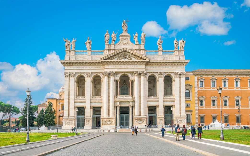 Facade of a Roman basilica on the Appian Way with visitors exploring the site.