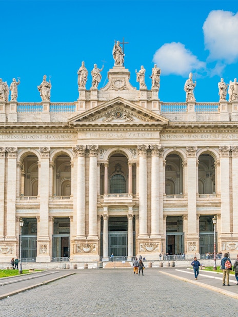 Facade of a Roman basilica on the Appian Way with visitors exploring the site.