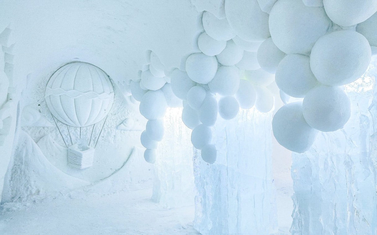 Arctic SnowHotel interior with ice sculptures and snowball ceiling design.