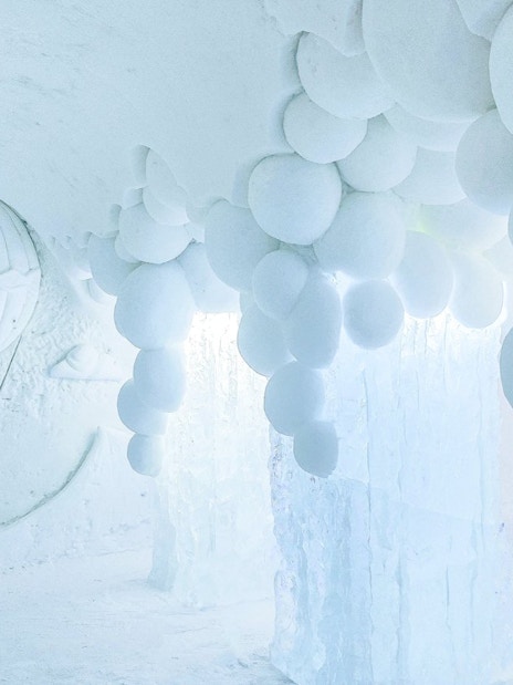 Arctic SnowHotel interior with ice sculptures and snowball ceiling design.