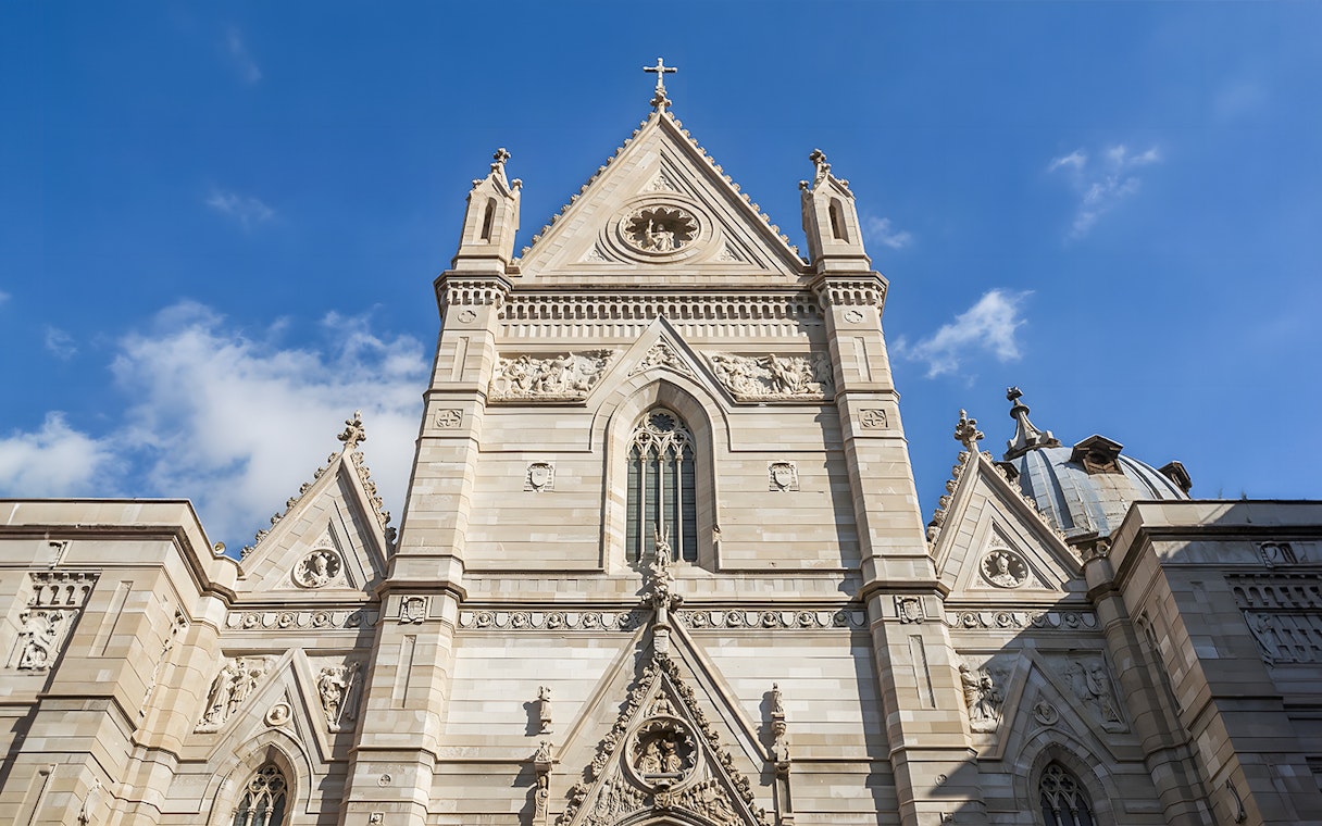 Sansevero Chapel facade with intricate sculptures and architectural details under a blue sky.