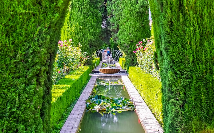 Alhambra garden path with fountain and hedges, Granada, Spain.