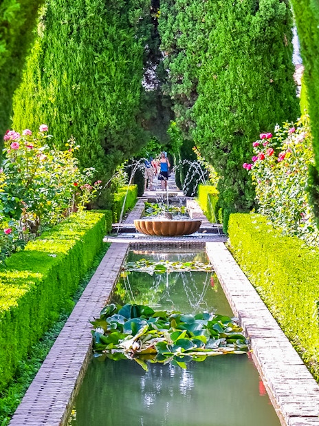 Alhambra garden path with fountain and hedges, Granada, Spain.