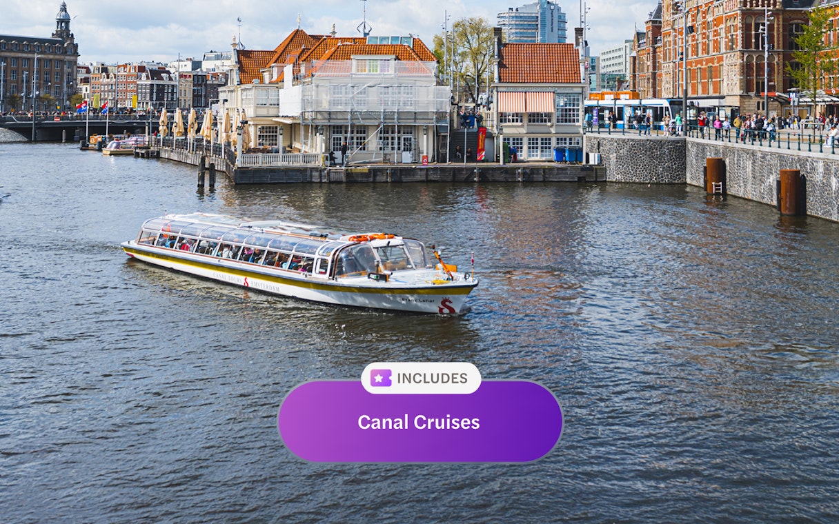Canal cruise boat on Amsterdam canal with historic buildings in the background.
