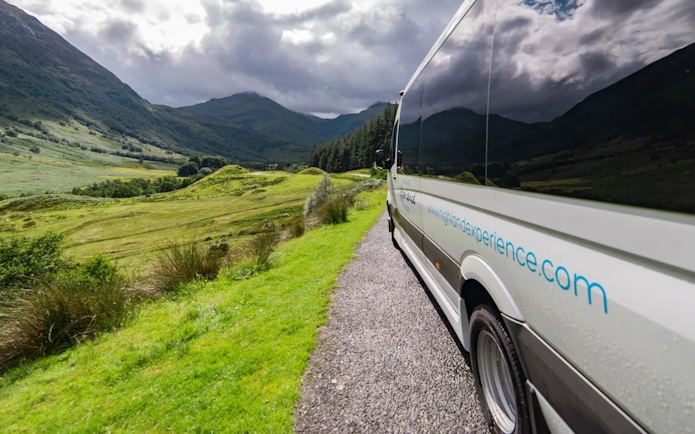 Transfer vehicle on scenic route through Scottish Highlands.
