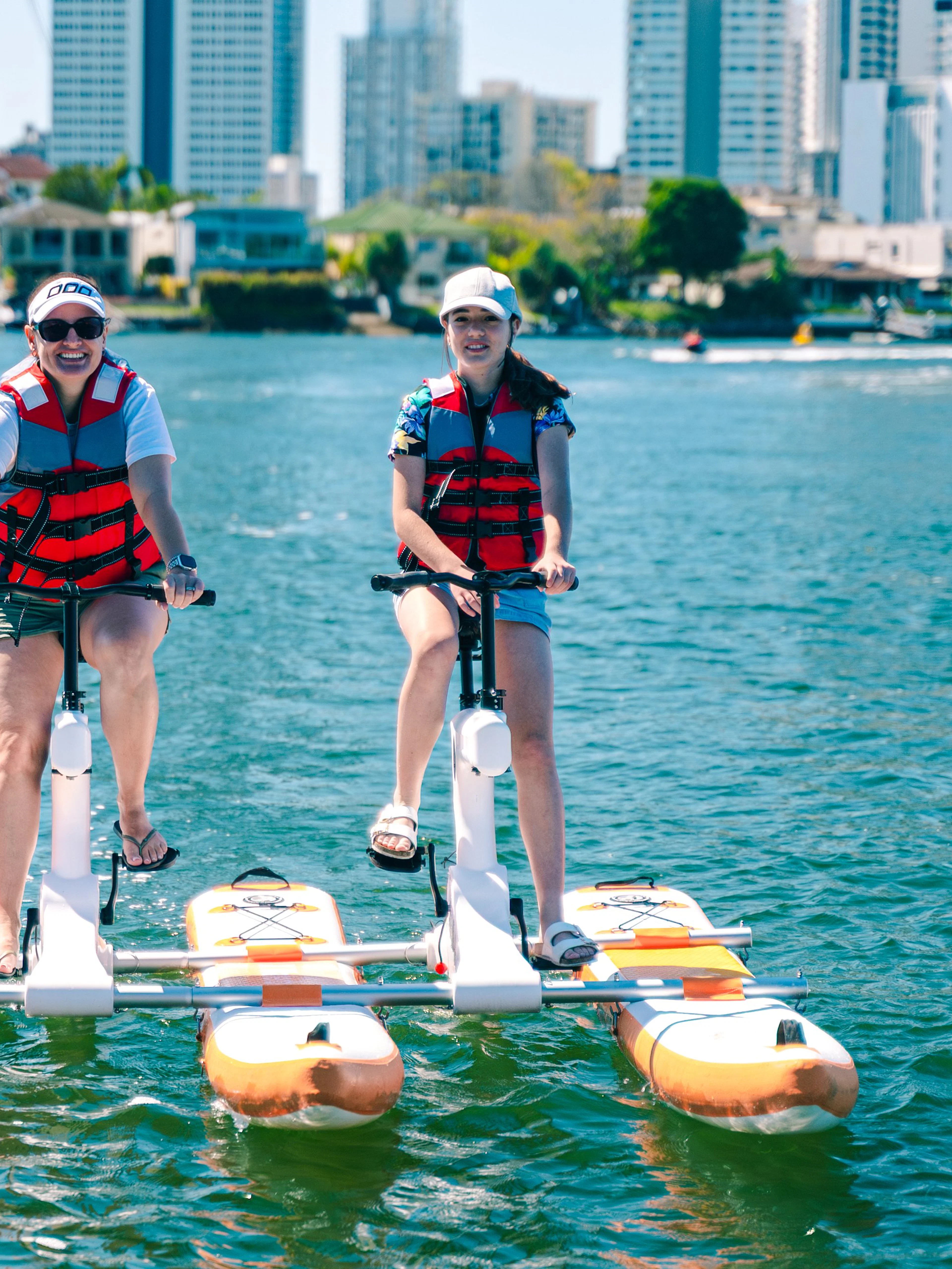 Tourists riding waterbikes on the Gold Coast with city skyline in the background.