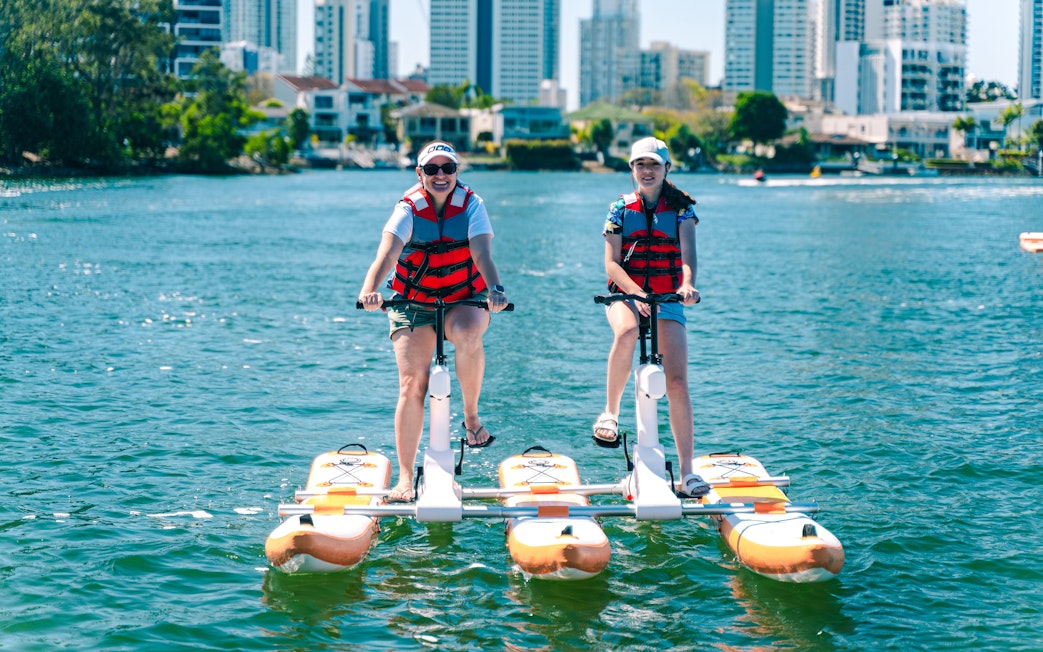 Tourists riding waterbikes on the Gold Coast with city skyline in the background.