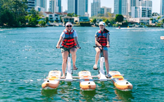 Tourists riding waterbikes on the Gold Coast with city skyline in the background.