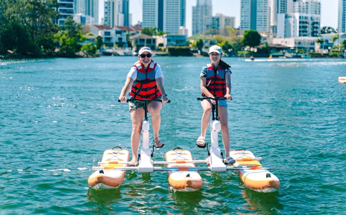 Tourists riding waterbikes on the Gold Coast with city skyline in the background.