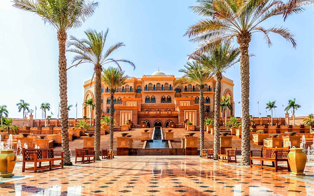 Emirates Palace entrance with palm trees and fountains, Abu Dhabi.
