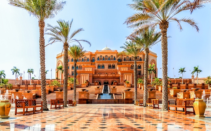 Emirates Palace entrance with palm trees and fountains, Abu Dhabi.