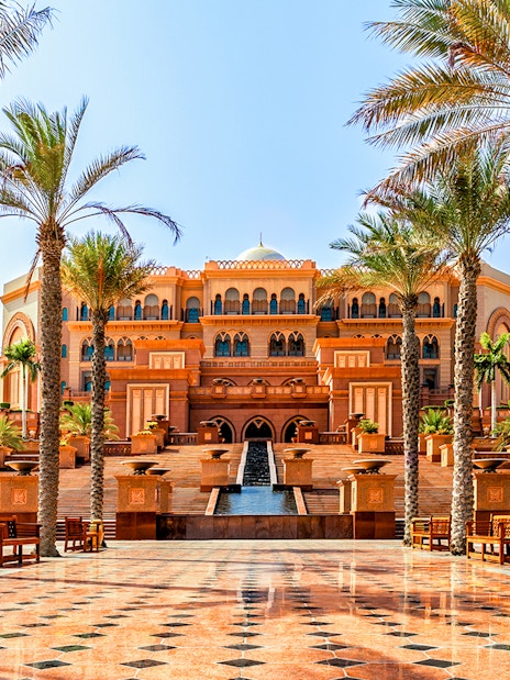 Emirates Palace entrance with palm trees and fountains, Abu Dhabi.