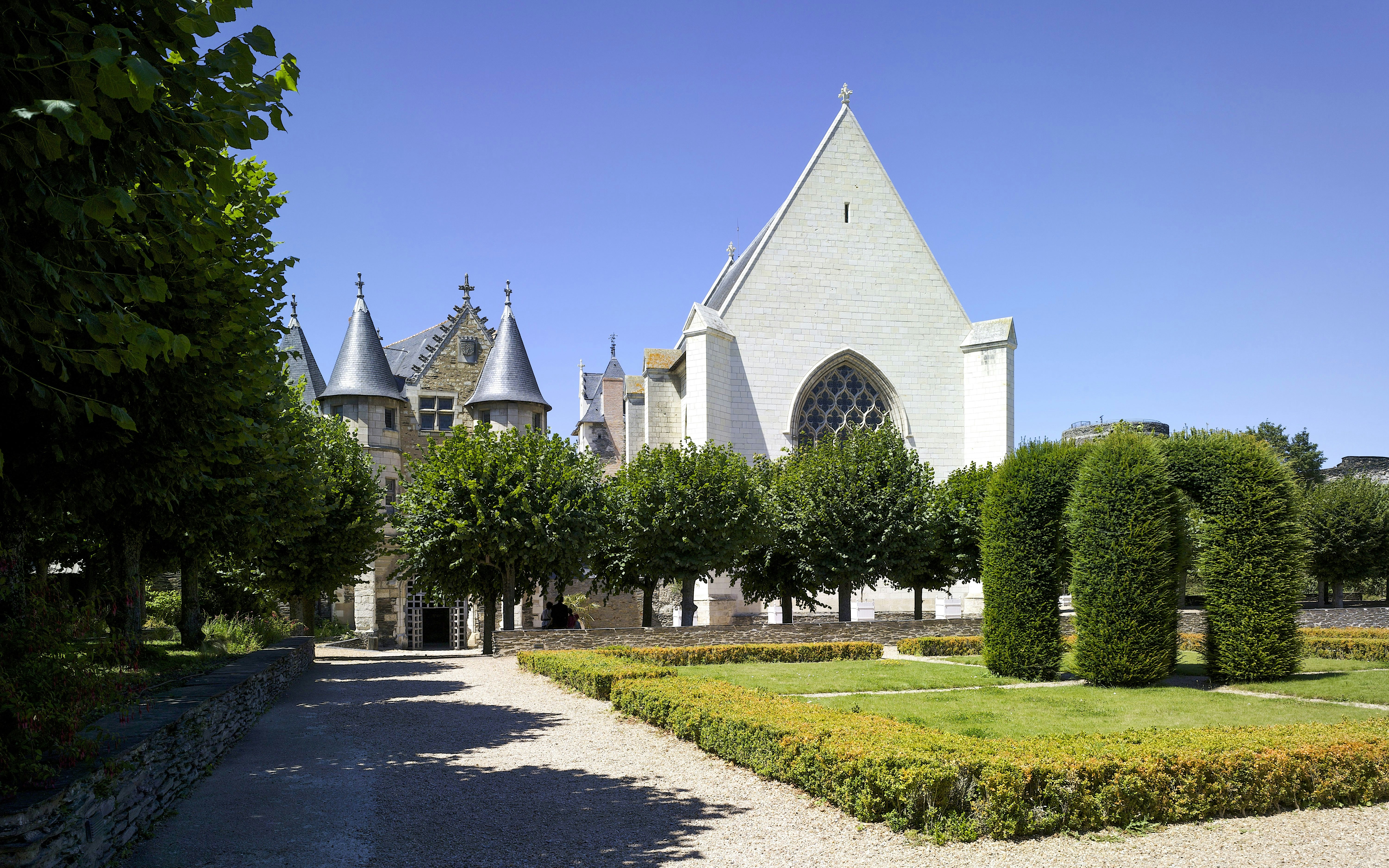 Château d’Angers garden with medieval architecture and manicured hedges in Angers, France.