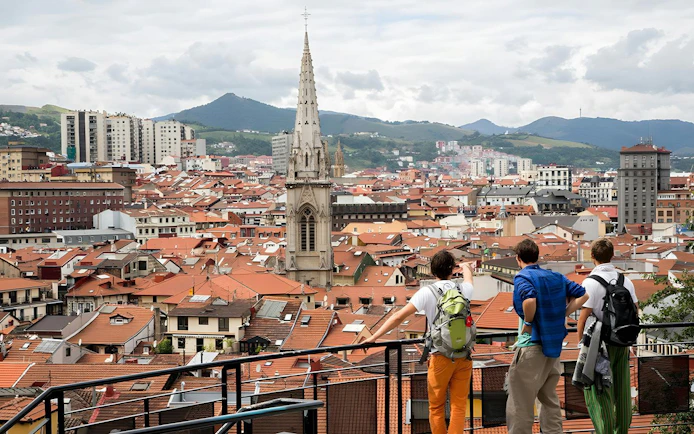 Panoramic view of Bilbao's Casco Viejo with Santiago Cathedral spire and terracotta rooftops.