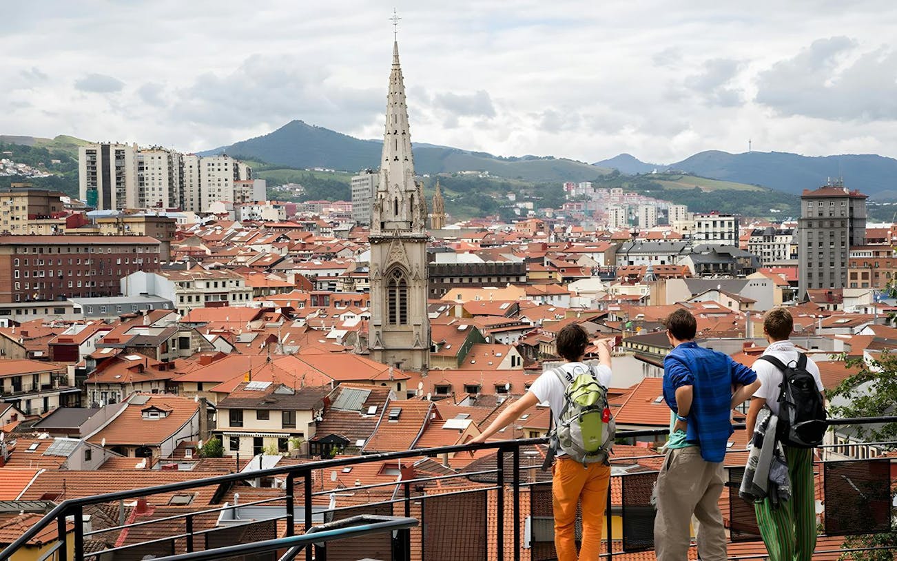 Panoramic view of Bilbao's Casco Viejo with Santiago Cathedral spire and terracotta rooftops.