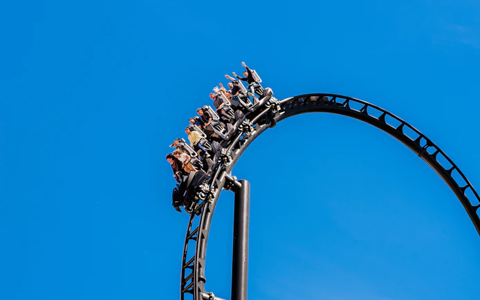 Roller coaster loop with riders at Batman Gotham City Escape, Parque Warner Madrid.