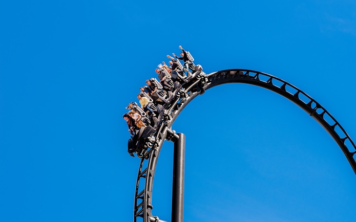 Roller coaster loop with riders at Batman Gotham City Escape, Parque Warner Madrid.