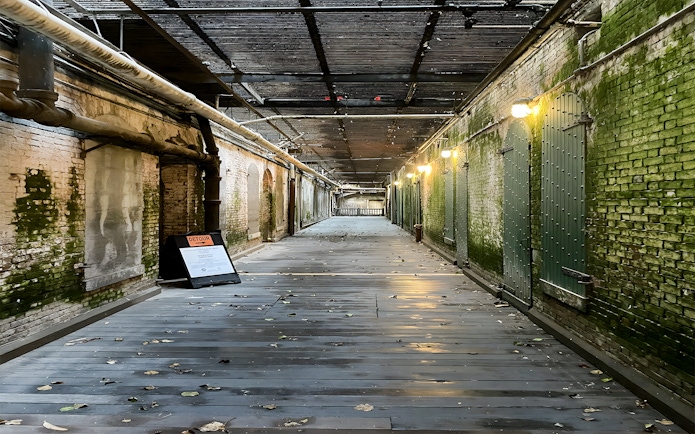 Walkway to prison cells with mossy walls on Alcatraz Island, San Francisco.