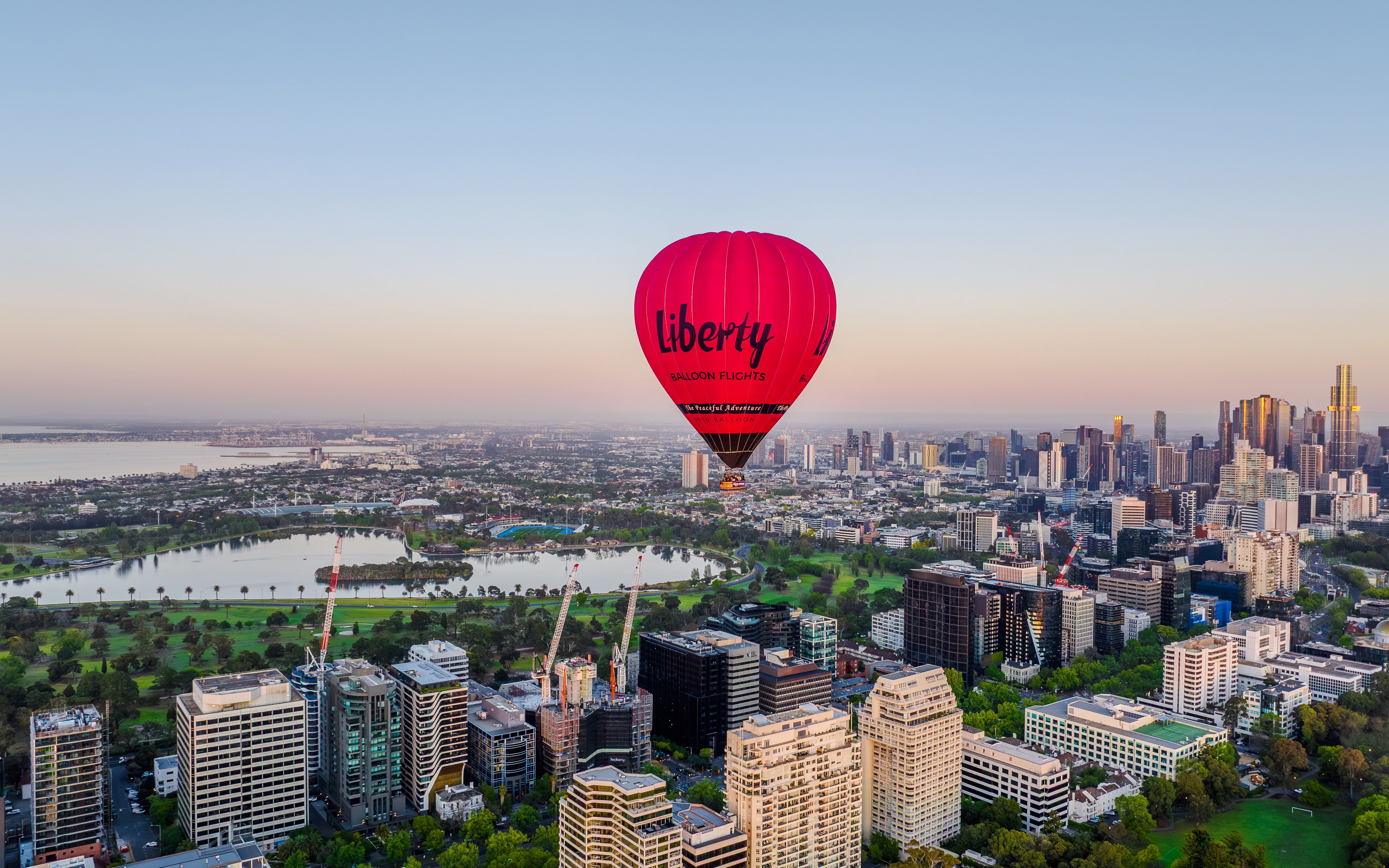 Hot air balloon over Melbourne skyline at sunrise.