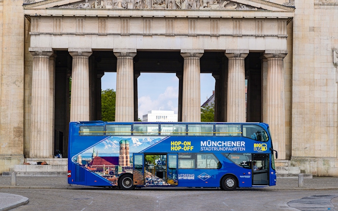 Hop-On Hop-Off bus in front of Munich landmark on tour route.