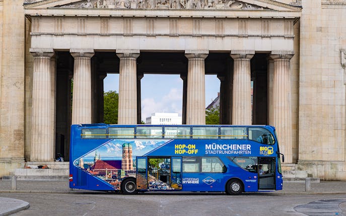 Hop-On Hop-Off bus in front of Munich landmark on tour route.