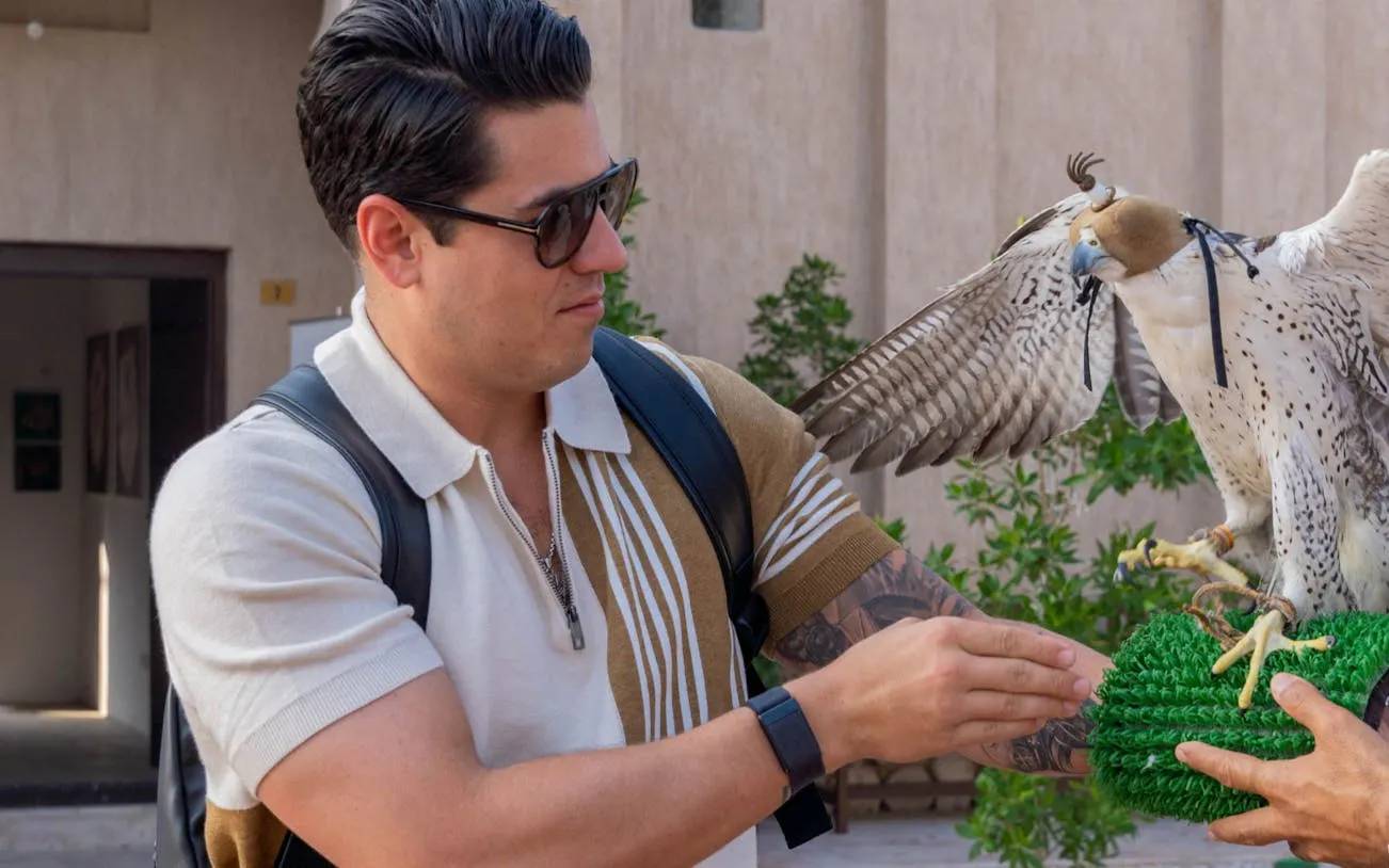 Man interacting with a falcon during a cultural storytelling tour in Dubai.