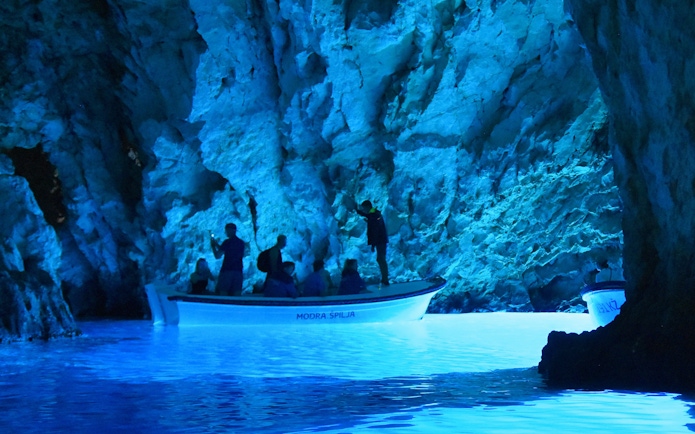 Boat tour inside Blue Cave, Croatia with illuminated blue waters.