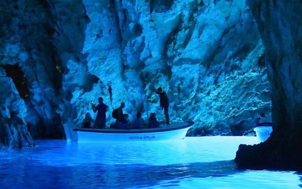 Boat tour inside Blue Cave, Croatia with illuminated blue waters.