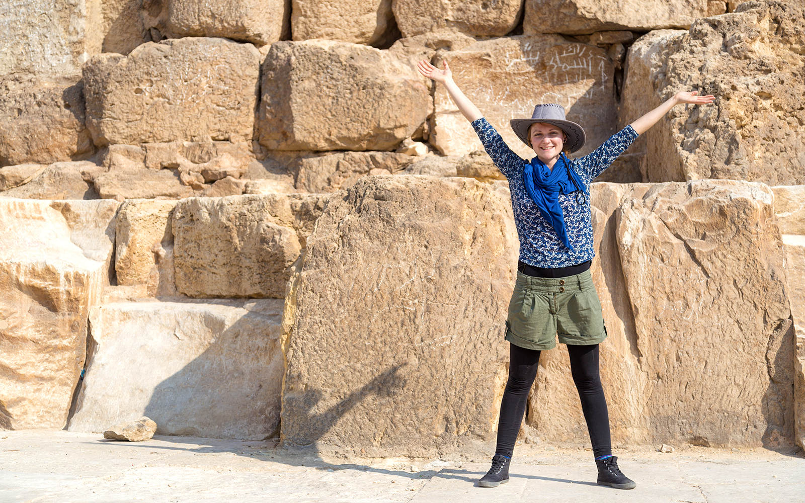 Tourist with arms raised in front of The Great Pyramid of Giza, Egypt.