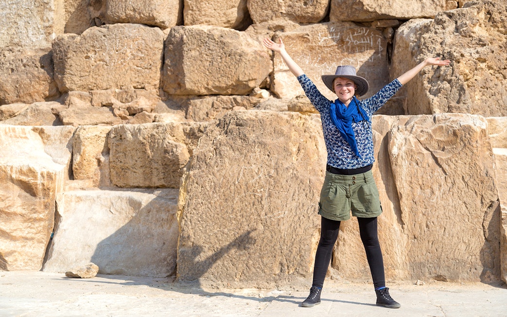 Tourist with arms raised in front of The Great Pyramid of Giza, Egypt.