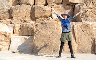 Tourist with arms raised in front of The Great Pyramid of Giza, Egypt.
