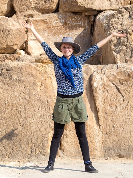 Tourist with arms raised in front of The Great Pyramid of Giza, Egypt.