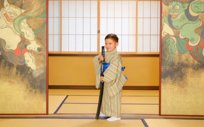Child in kimono holding sword in traditional Japanese room.