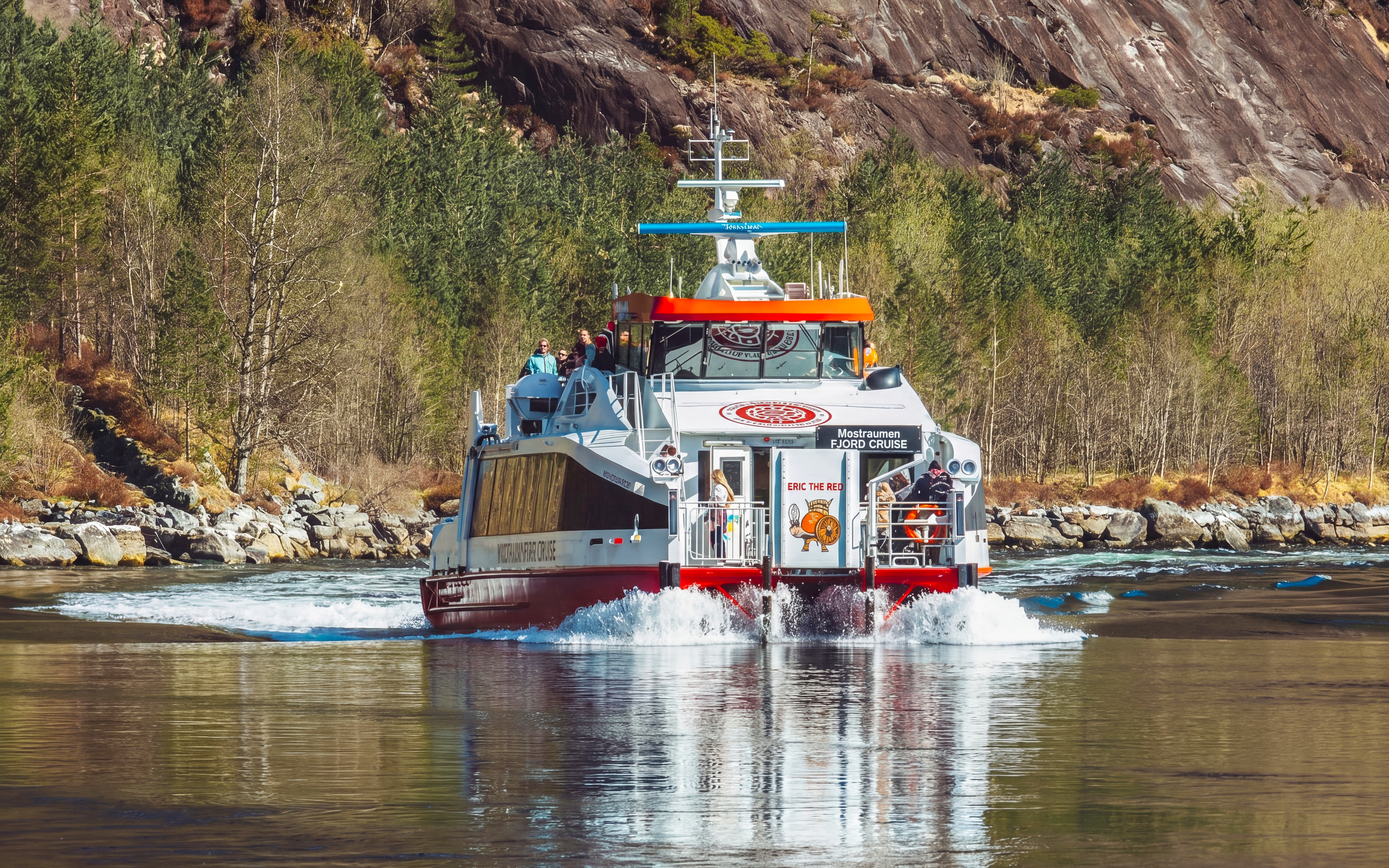 Cruise boat on Mostraumen Fjord near Bergen with passengers enjoying scenic views.