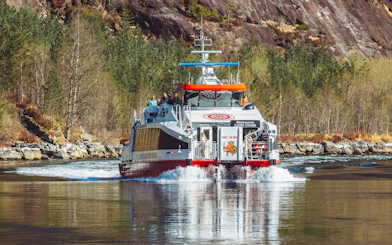 Cruise boat on Mostraumen Fjord near Bergen with passengers enjoying scenic views.