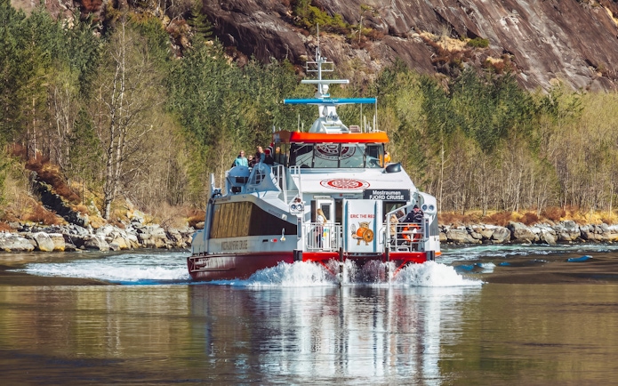 Cruise boat on Mostraumen Fjord near Bergen with passengers enjoying scenic views.