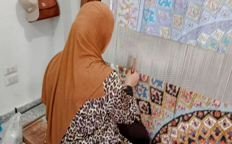 Person weaving a colorful carpet at Khan el-Khalili market, Cairo.