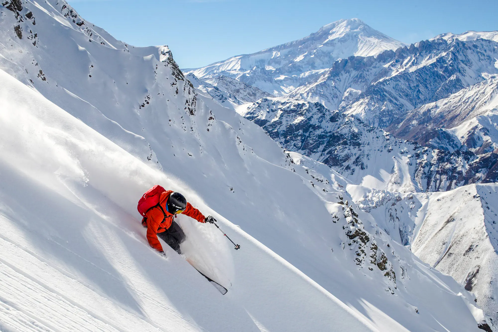 Skier descending snowy slope at Valle Nevado with Andes mountains in background, Santiago.