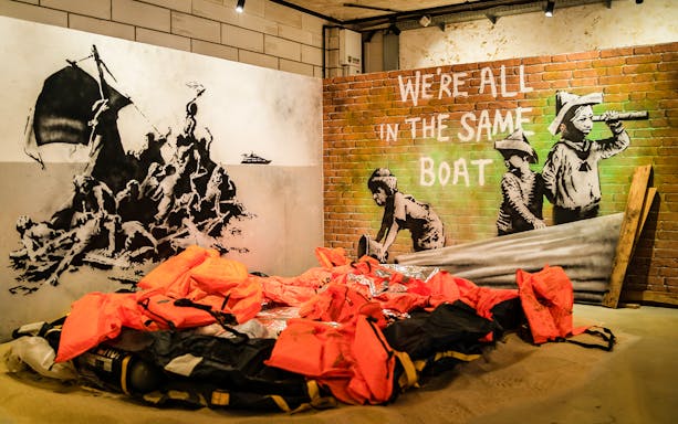 Banksy artwork with life jackets and "We're all in the same boat" at Krakow museum.