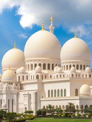 Sheikh Zayed Grand Mosque with white domes and minarets under a blue sky in Abu Dhabi.