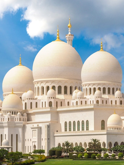 Sheikh Zayed Grand Mosque with white domes and minarets under a blue sky in Abu Dhabi.