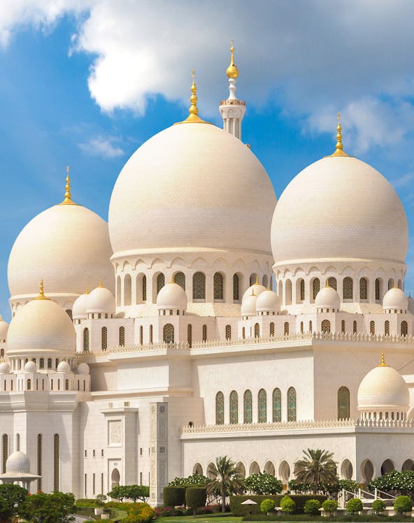 Sheikh Zayed Grand Mosque with white domes and minarets under a blue sky in Abu Dhabi.